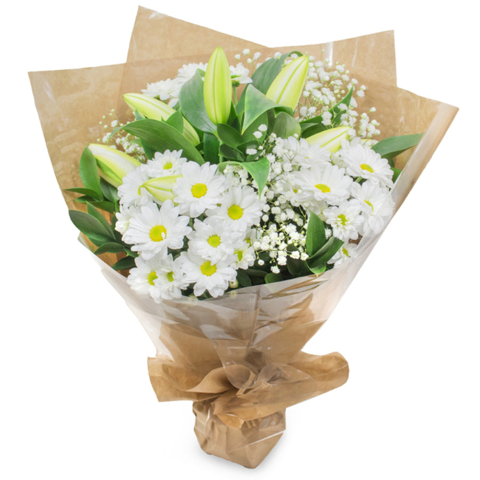 An elegant, fresh bouquet presented upright on a white field, fashioned from a harmonious chorus of white and green. Dominant are the daisy-like chrysanthemums: dozens of crisp white petals arranged around modest yellow centers, their regular, joyful faces forming the visual heart of the design. Interspersed among them are slim, pale green-yellow lily buds, some with faint linear markings, their unopened shapes lending a refined anticipation to the bouquet and promising a slow, gracious bloom. Sprays of fine, white Gypsophila (baby's breath) float through the composition, adding wispy texture and softening transitions between the larger blooms. Lush, deep-green foliage provides contrast and depth, a verdant stage that makes the whites appear crisper and more luminous. The stems have been gathered and hand-tied, then wrapped in an inner layer of tactile, crinkled brown kraft paper and an outer sheet of clear cellophane that protects while allowing the flowers to be fully visible; the wrapping is folded and secured at the base to form a neat carrying support. The overall scent is delicate and clean, an unobtrusive freshness that suits both celebration and consolation. Crafted with an attentive hand in a local East Finchley studio close to Fortis Green and the busy High Road, this bouquet reads as versatile and sincere - an appropriate offering for anniversaries, thank-you gestures, hospital visits, or a tasteful centerpiece for a small gathering in a nearby home.