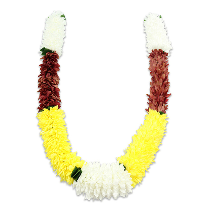 A vividly coloured malas-style garland is displayed in a gentle U-shape on a bright white field, the faint shadow underneath lending it depth and presence. Constructed from thousands of individual fabric petals, the garland is deliberately durable for ceremonial use: short crowns of compact white flowers cap each upper arm, followed by dense bands of maroon or reddish-brown that ground the design, and then long, sunny-yellow stretches that form the broad curve and visual warmth of the whole. Where the two yellow arms meet at the bottom, a large cluster of pure white chrysanthemum-like blooms creates a satisfying focal knot, while small, dark-green leaf accents act as delicate separators between colour blocks, especially between the yellow and lower white segments. The surfaces of the fabric blooms have a soft matte texture, stitched and layered to mimic natural petal overlaps, and the overall proportion keeps the garland feeling abundant yet balanced. This arrangement speaks directly to ceremonial needs - suitable for Hindu pujas, temple offerings, wedding mandaps, or festival decorations like Diwali and Holi - with colours traditionally read as purity, prosperity and devotion. Seen through the eyes of a local floral maker, this is the sort of handcrafted, resilient garland you might order for an East Finchley community celebration, a home shrine near the tube station, or for a church hall event on the High Road; its craftsmanship and cultural resonance make it a thoughtful and practical decorative element.